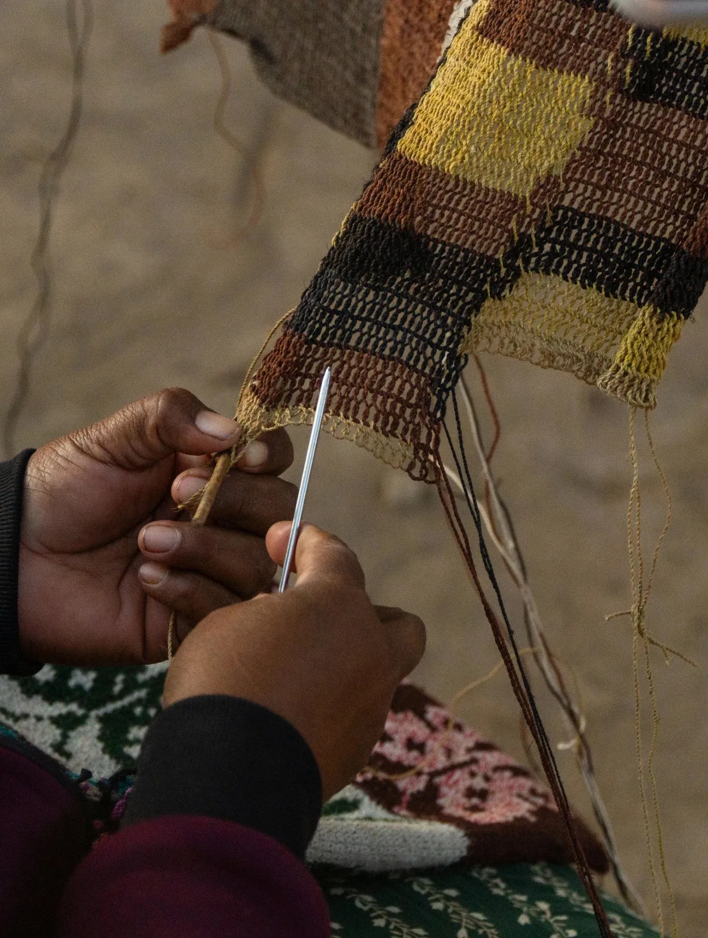 Hands weaving spun chaguar fibres into a patterned textile